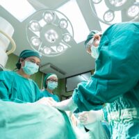 Three doctors performing surgery, while wearing personal protective equipment